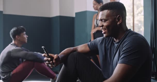 Afrikanischer Mann Lächelt Fitnessstudio Auf Sein Handy Hochwertiges Filmmaterial — Stockvideo