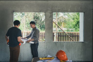 Mühendis ve mimar inşaat alanındaki projeyi ustabaşıyla tartışıyor.