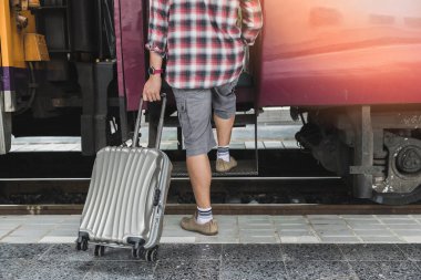 Traveler with baggage is stepping up the train in train station. Transportation concept.