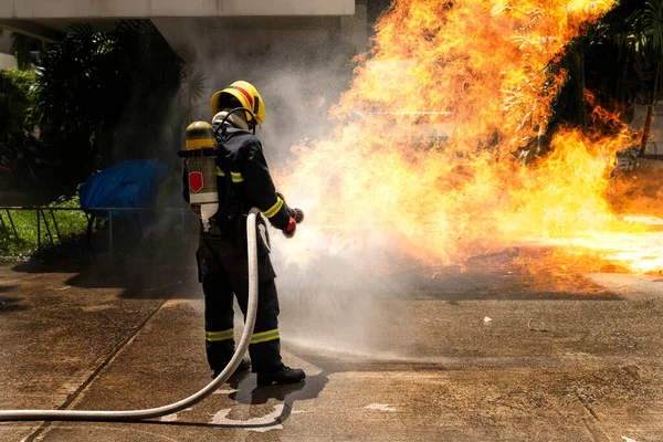 Pompiers Avec Extincteur Pulvérisant Eau Haute Pression Pour Combattre Flamme Photos De Stock Libres De Droits
