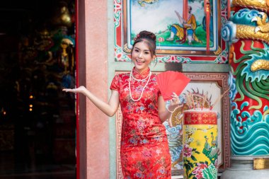 Çin Yeni Yılı 'nı kutlamak için: Kırmızı Cheongsam (qipao) elbiseli Çinli kadın tapınakta kırmızı zarflar (hong bao) taşıyor..