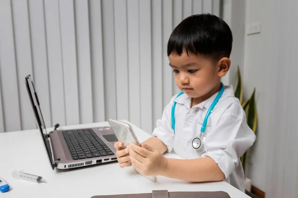 Little Boy Medic Uniform Using Cellphone Desk — 스톡 사진