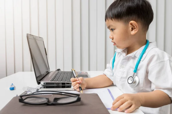 Kleiner Junge Sanitätsuniform Hält Einen Stift Auf Dem Schreibtisch — Stockfoto