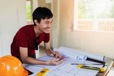 İnşaat alanının planında cep telefonu kullanan mühendis ya da mimar.