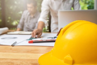 Masanın üzerindeki miğferin imajını, mimari konsept projesiyle çalışan mimarlarla kapatın..