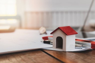 İş, mimarlık, inşaat ve inşaat konsepti - Mimarlık masasının üzerinde ölçüm aracı ve planları olan ev modelleri