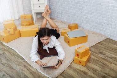 Asyalı kadın evde halıda yatarken dizüstü bilgisayarla çalışıyor..