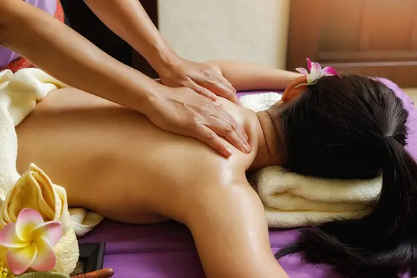 Asian woman enjoying back massage in massage salon. Beauty treatment concept.