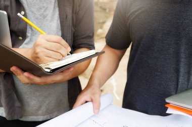 İnşaat işçileri, proje detaylarını inşaat alanındaki planlarla tartışıyor..
