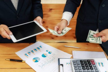 İş adamı ortağına para veriyor. Rüşvet ve yolsuzluk kavramları. Adamın biri tablet alması için bir satıcıya para verdi..