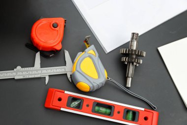 Ölçüm aracı, bant, seviye ve vernier kalibreli teçhizatın mühendislik masasında üst görünümü.