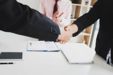 İş adamları el sıkışıyor, toplantıyı bitiriyor. Ofiste bir toplantı sırasında el sıkışan iki emin iş adamı, başarı, anlaşma, tebrik ve ortak kavramı.