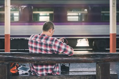 Tren istasyonunda kameralı bir gezgin oturuyor. Klasik tonda seyahat kavramı.