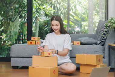 Paket paketleyen bir kadın. Başarılı girişimci iş kadını çevrimiçi satışları ve paket taşımacılığı ile ev ofisinde.