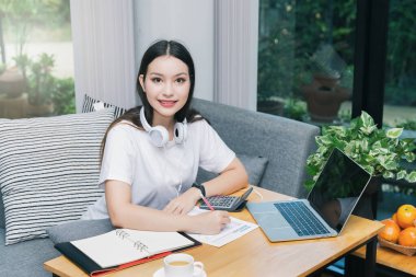 Kulaklıklı genç bir öğrenci internetten dersini izliyor ve evden ders çalışıyor. Bilgisayarı kullanıyor ve internetten öğreniyor. Uzaklık öğrenimi çevrimiçi eğitim.