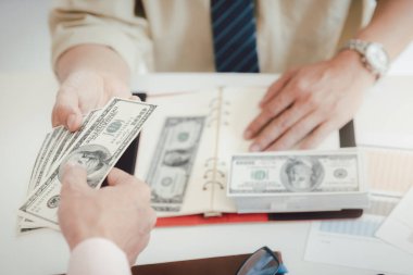 Adam yüz dolarlık banknotlar teklif ediyor. Ortağına para veren bir işadamının eli. İş adamından el ile para almak. Venality, rüşvet, yolsuzluk konsepti.