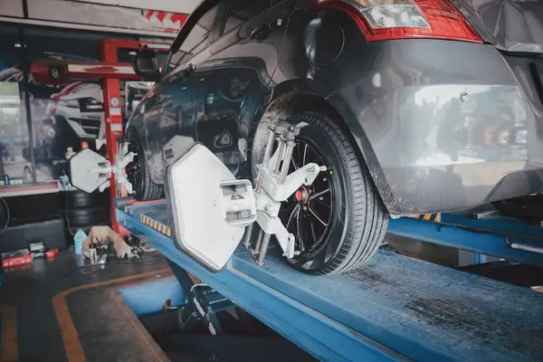 Araç tekerleği dengeleyicisi, her lastiğe lazer yansıtıcı takılı olarak ayarlansın. Araba serviste. Dengeleyici tekerlek makinesi.