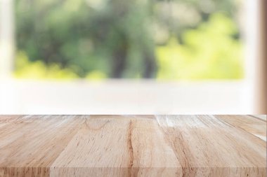 Boş ahşap masa, sabahları bahçeden ve pencereden soyut yeşil bokeh. Montaj ürünü görüntüleme veya tasarım için görsel anahtar düzeni.