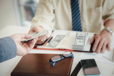 Adam yüz dolarlık banknotlar teklif ediyor. Ortağına para veren bir işadamının eli. İş adamından el ile para almak. Venality, rüşvet, yolsuzluk konsepti.