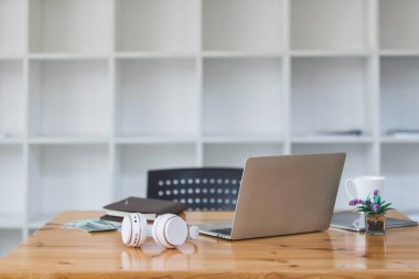Laptop, kulaklık, saksı, para ve benzeri şeyler ofisteki masada. Dizüstü bilgisayar ve ofis malzemeleriyle çalışma alanı.