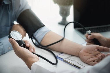 Hastanedeki hastanın kan basıncını ölçen doktor, tıbbi ve sağlık konseptleri.