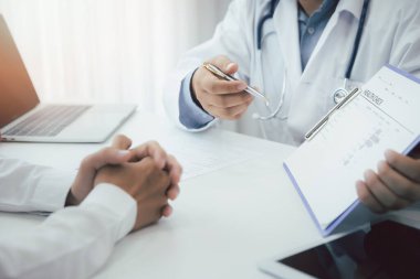 Bir doktor danışmanı ve hasta sağlığı muayenesini ofiste açıklar. İlaç ve sağlık hizmetleri kavramı.