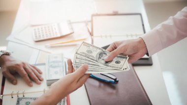 Adam yüz dolarlık banknotlar teklif ediyor. Ortağına para veren bir işadamının eli. İş adamından el ile para almak. Venality, rüşvet, yolsuzluk konsepti.