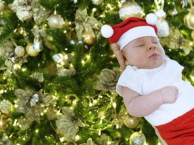 A tender moment of a baby boy peacefully sleeping in his mothers arms, dressed in an adorable Christmas outfit. The scene radiates warmth, love, and the festive spirit. clipart