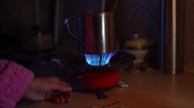 Bir kız mum ışığında gaz ocağını yakıyor ve elektriksiz para sayıyor. Ukrayna 'da Savaş