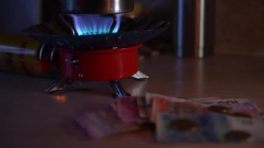 Bir kız mum ışığında gaz ocağını yakıyor ve elektriksiz para sayıyor. Ukrayna 'da Savaş