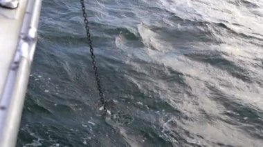 Raising the anchor chain on a white yacht. Slow motion