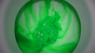 Dirty green water is poured into a white toilet. slow motion