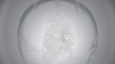 Clean water is poured into a white toilet. slow motion