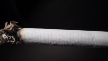 Siyah arka plan için sigara filtresi olan bir sigara. Yakın plan. Dolly vurdu.