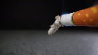 Siyah arka plan için sigara filtresi olan bir sigara. Yakın plan. Dolly vurdu.
