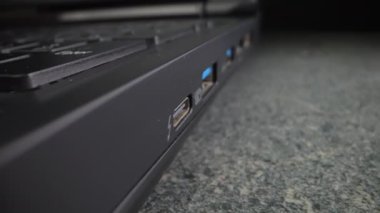 USB kablosu eski siyah bir dizüstü bilgisayara yerleştirilmiş. Yakın plan. Dolly vurdu.
