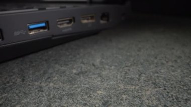USB kablosu eski siyah bir dizüstü bilgisayara yerleştirilmiş. Yakın plan. Dolly vurdu.