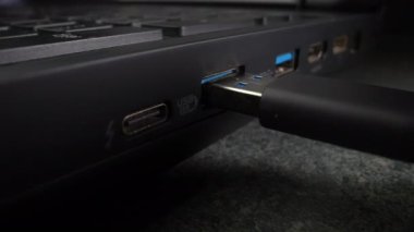 USB kablosu eski siyah bir dizüstü bilgisayara yerleştirilmiş. Yakın plan. Dolly vurdu.