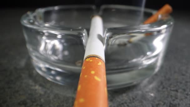 オレンジ色のフィルター付きのタバコは灰皿の中でくすぶっている 接近中だ ドリーショット — ストック動画