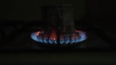 100 dolarlık banknot bir gaz sobasında yanıyor. Ağır çekim. Dolly vurdu.