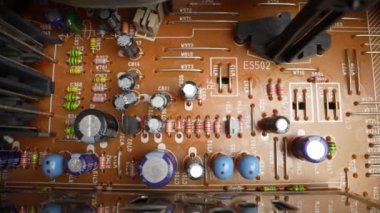 Eski bir video oynatıcısının radyo parçalarıyla dolu eski bir devre kartı. Dolly vurdu. Yakın plan.