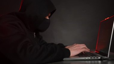 Hacker karanlık bir odada dizüstü bilgisayarla çalışıyor. Dolly vurdu.