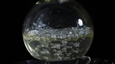 Sıvı, gaz ocağında bir laboratuvar şişesinde kaynıyor. Laboratuvarda uyuşturucu al. Kimyasal reaksiyon. Yavaş çekim