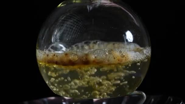 ブラウンの微粒は沸騰溶液でガラスの実験室のフラスコに注ぎ込まれています 化学反応について スローモーション — ストック動画