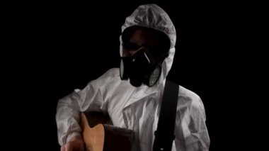 Solunum cihazı ve gözlüklü bir adam siyah arka planda gitar çalıyor.
