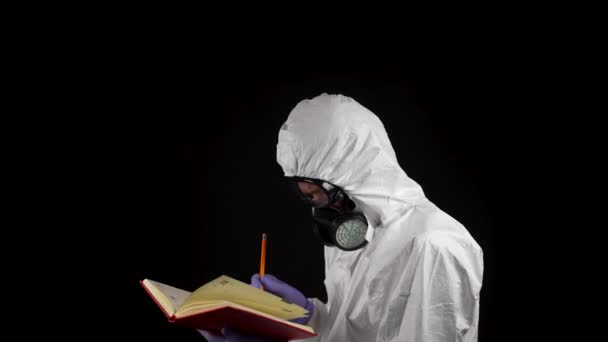 Лабораторний Працівник Костюмі Хімічного Захисту Пише Блокноті Олівцем Чорному Тлі — стокове відео