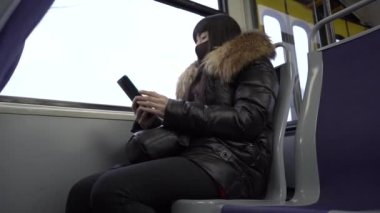 Coronavirüs salgını sırasında maske takan bir kız. Akıllı telefonlara bakan bir kız. Yavaş çekim