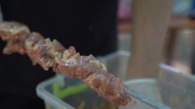 Aşçı eti şiş kebap şişlerine bağlar. Yavaş çekim
