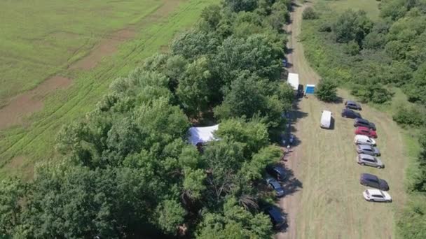 テントの下の森ベルトの畑の農民集団を集める ウクライナの空中ビデオ — ストック動画