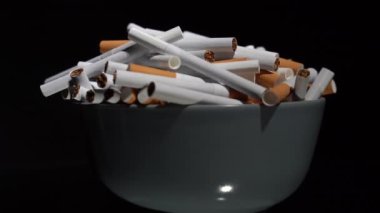 Sigaralar siyah arka planda dönen bir masanın üzerinde tabakta toplu halde.